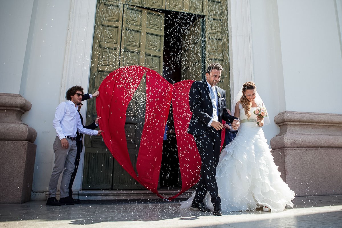 Sposi novelli kissing mentre si esce dalla chiesa dopo la cerimonia di  matrimonio, la famiglia e